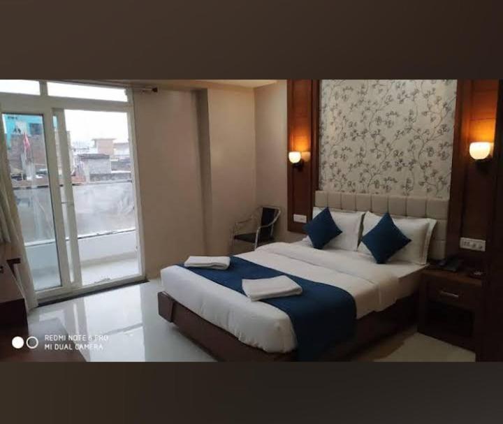 - une chambre avec un lit doté d'oreillers bleus et d'une fenêtre dans l'établissement Royal Aryan Hotel, à Purî