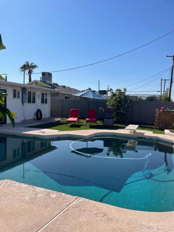 a swimming pool with two red chairs in a yard at Cozy Home with Sparkling Pool/Pet Friendly in Mesa