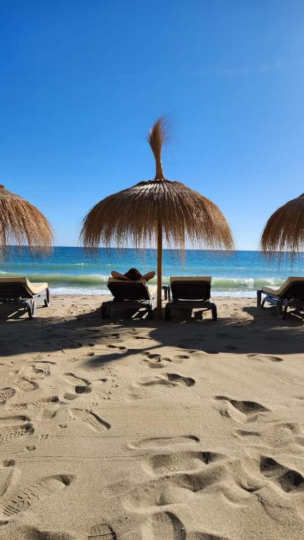 a beach with chairs and an umbrella and the ocean at Apartment Beachfront Accommodation in Estepona