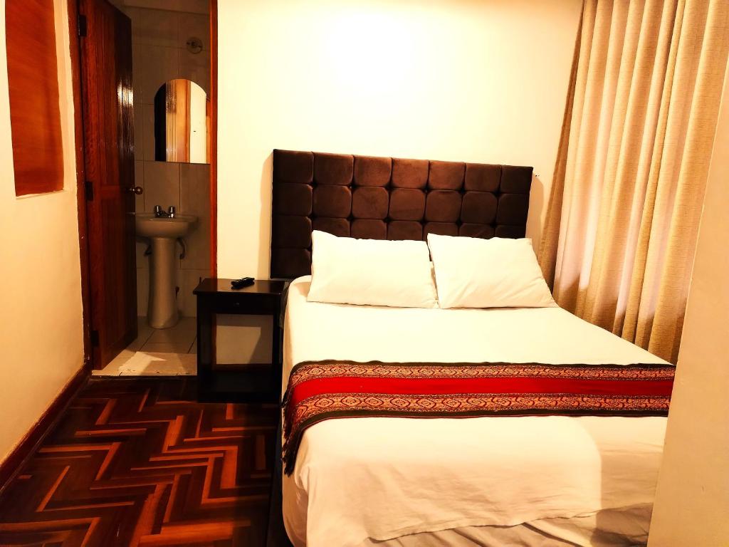 a bedroom with a bed with a brown headboard at Paqarina San Blas in Cusco