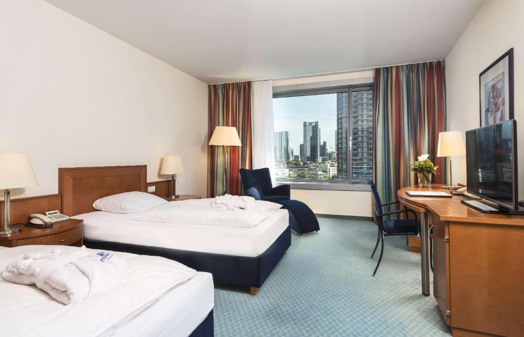 a hotel room with two beds and a television at Maritim Hotel Frankfurt in Frankfurt