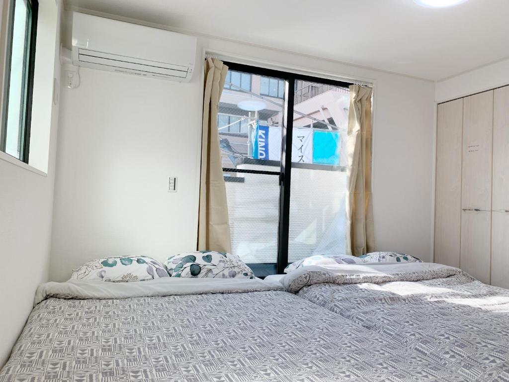 two beds in a room with a window at Shinjuku#ookubo#kabukicho#New built 3beds room,3 toilets, 2 shower rooms#新宿中心#大久保#歌舞伎#地铁站步行2分#新建公寓3层3卧室3卫生间2浴室1客厅#高速无限制网络#智能马桶#干湿分离103 in Tokyo
