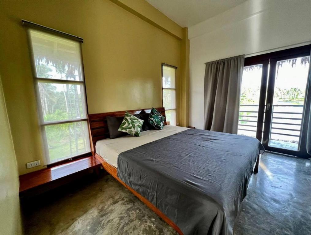 a bedroom with a bed and two windows at Siargao Wakepark in General Luna