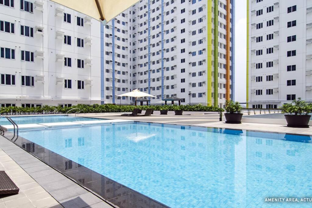 a large swimming pool in front of two tall buildings at Doc's Place 2 @MPlace with Wi-fi in Manila