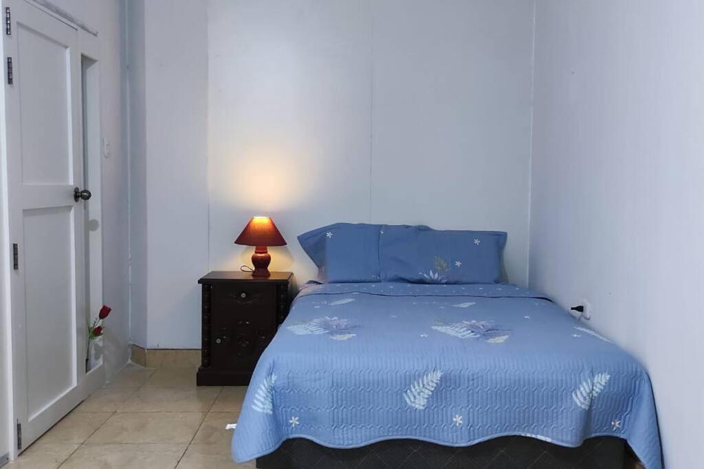 a bedroom with a blue bed with a lamp on a night stand at Acogedora habitación privada en Chiclayo. in Chiclayo
