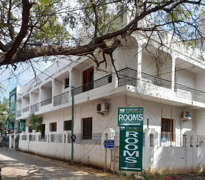 a white building with a sign in front of it at THE ALP HOTEL Bypass Road in Madurai