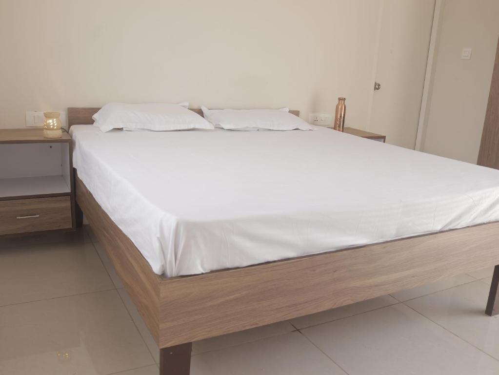 ein Bett mit weißer Bettwäsche und einem Holzrahmen in der Unterkunft swaastik stay in Rishikesh