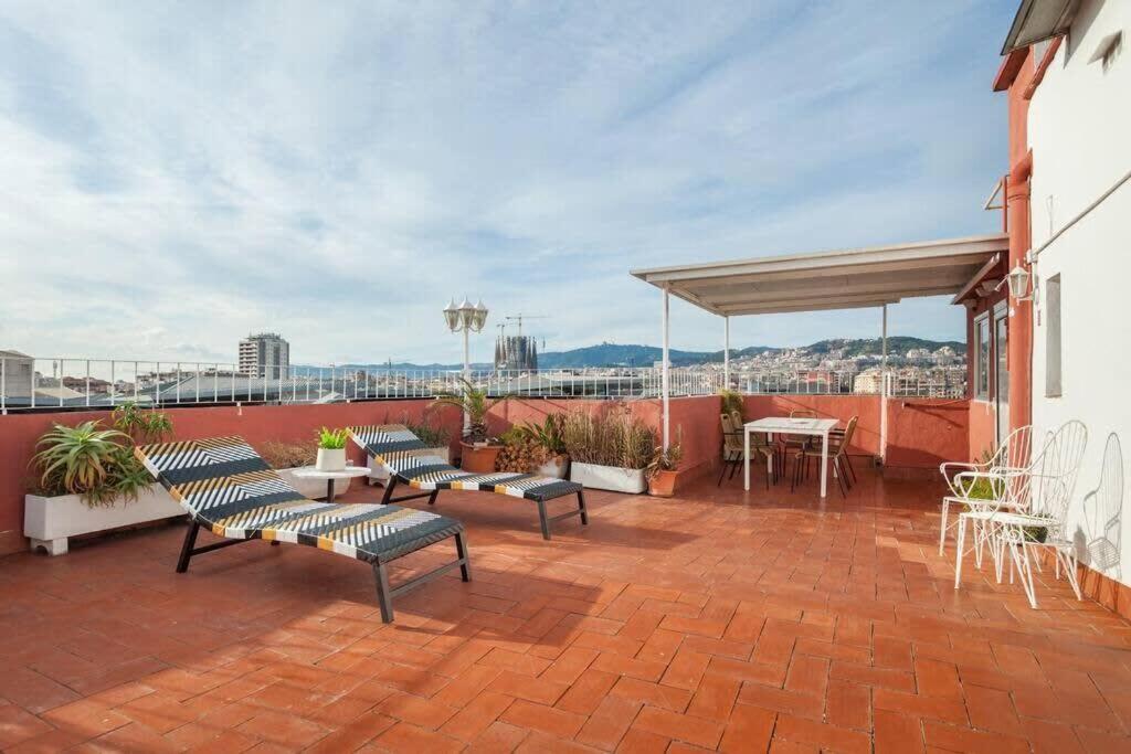 eine Terrasse mit Bänken, einem Tisch und Stühlen in der Unterkunft City View Penthouse - 2 Bedroom Suite in Barcelona