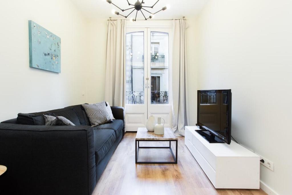een woonkamer met een zwarte bank en een tv bij Bright and modern 2bedroom in Las Ramblas 2 1A in Barcelona