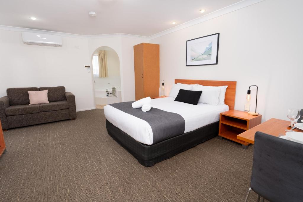 um quarto de hotel com uma cama grande e uma cadeira em Best Western Tuscany on Tor Motor Inn em Toowoomba