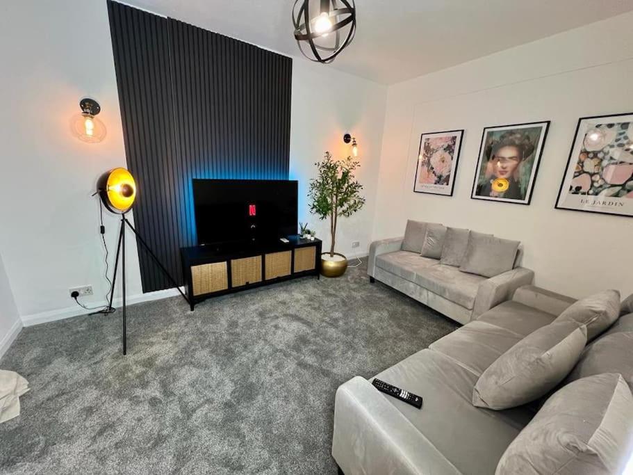 Il comprend un salon doté d'un canapé et d'une télévision à écran plat. dans l'établissement Cosy 4 Bed House, à Aldershot