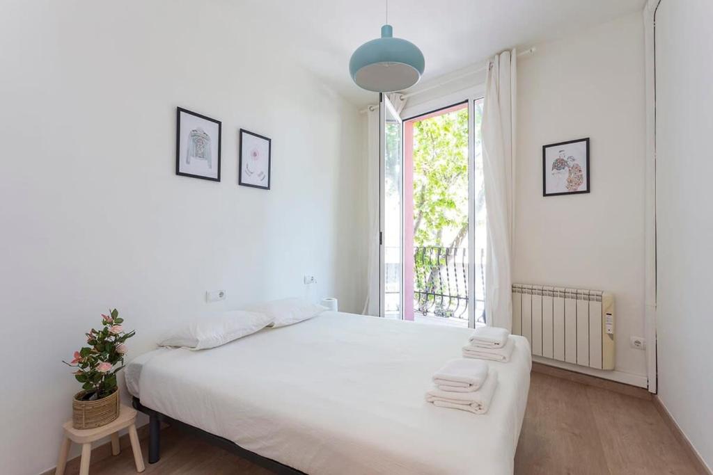 a white bedroom with a large bed and a window at Poblenou renovated 3BD next to the beach in Barcelona