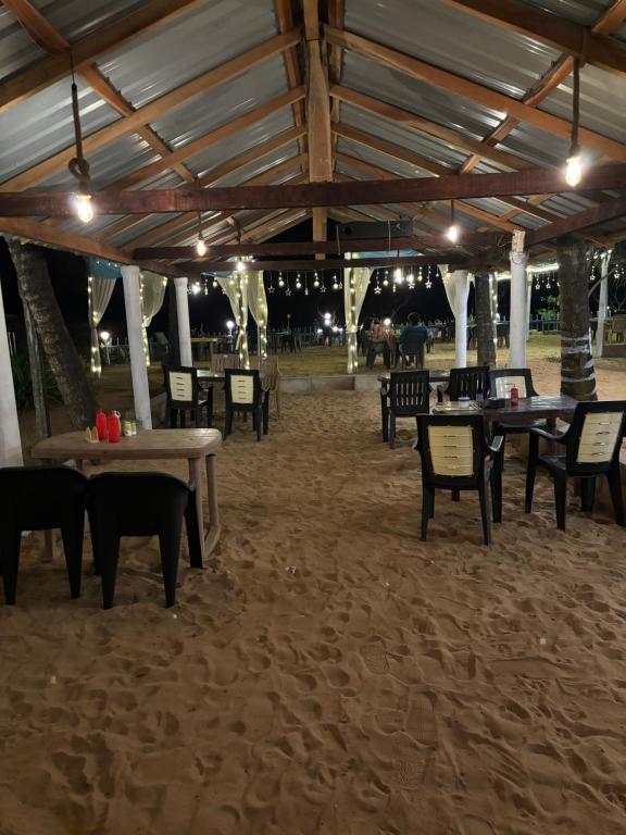 a patio with tables and chairs in the sand at Absolute paradise in Gokarna