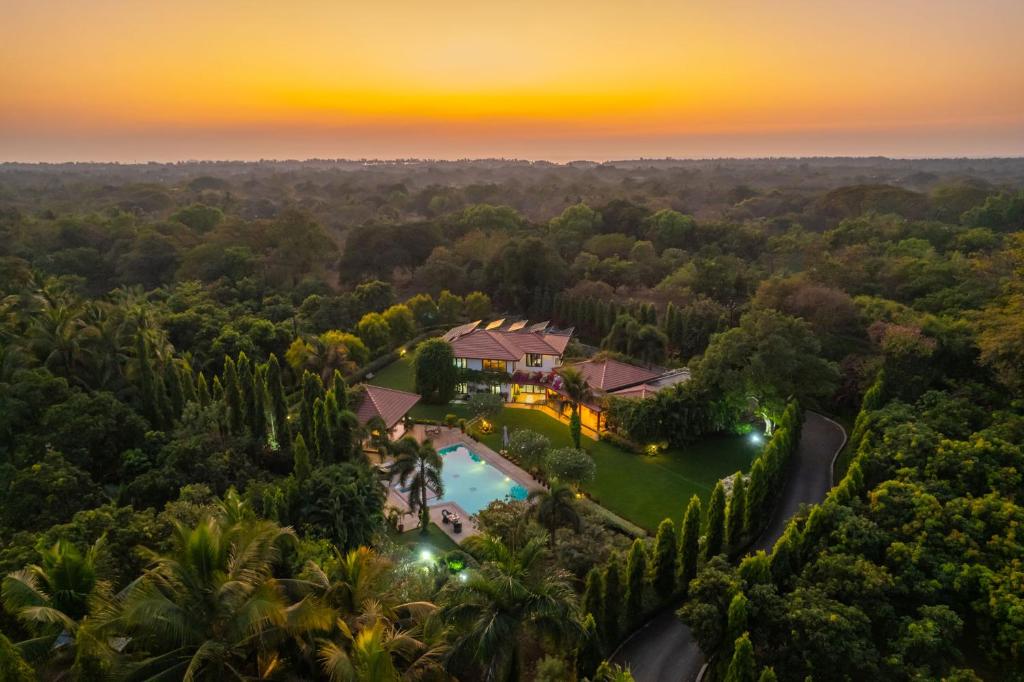 an aerial view of a villa with a swimming pool and a sunset at StayVista at Moksh Villa - BBQ & Jacuzzi in Alibaug