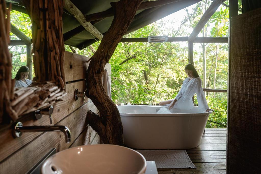 uma mulher sentada numa banheira num quarto em Summerfields Rose Retreat and Spa em Hazyview