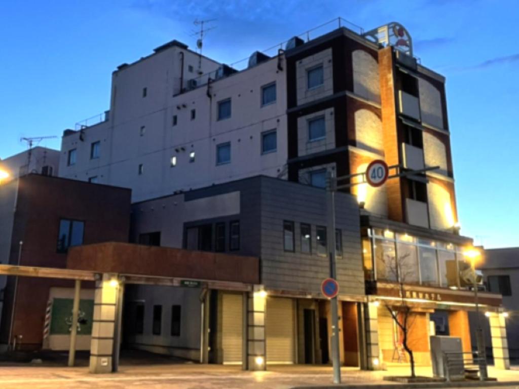 a large building is lit up at night at Tabist Hirosaki Touei Hotel in Hirosaki