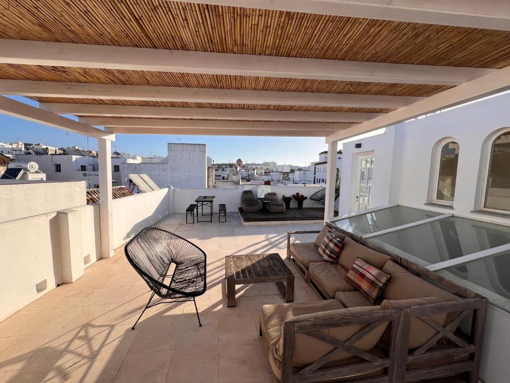 a patio with a couch and chair on a roof at Apartamentos Caravane in Tarifa