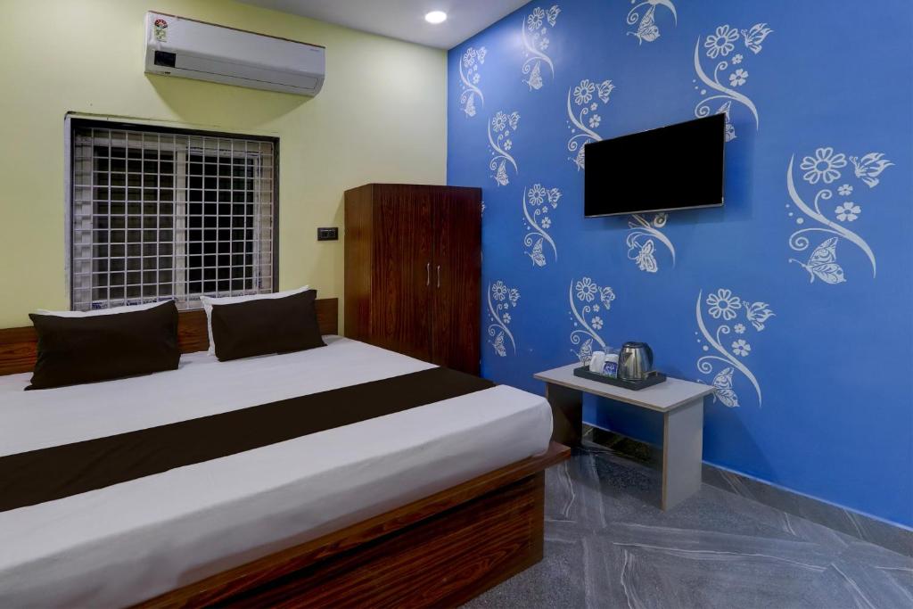 1 dormitorio con 1 cama y TV en una pared azul en OYO Flagship SRI JOGULAMBA RESIDENCY, en Bālānagar