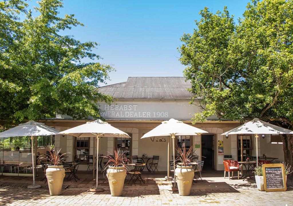 a restaurant with tables and umbrellas in front of it at Via's Guesthouse in Greyton