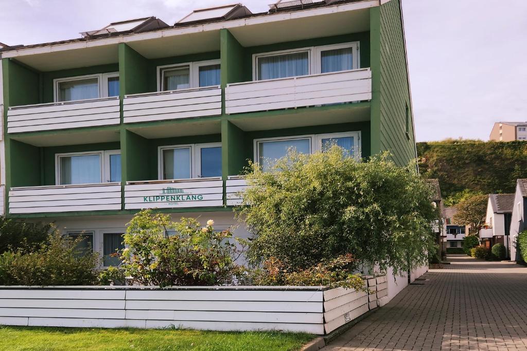 un edificio verde y blanco con arbustos delante de él en Hotel Klippenklang en Helgoland