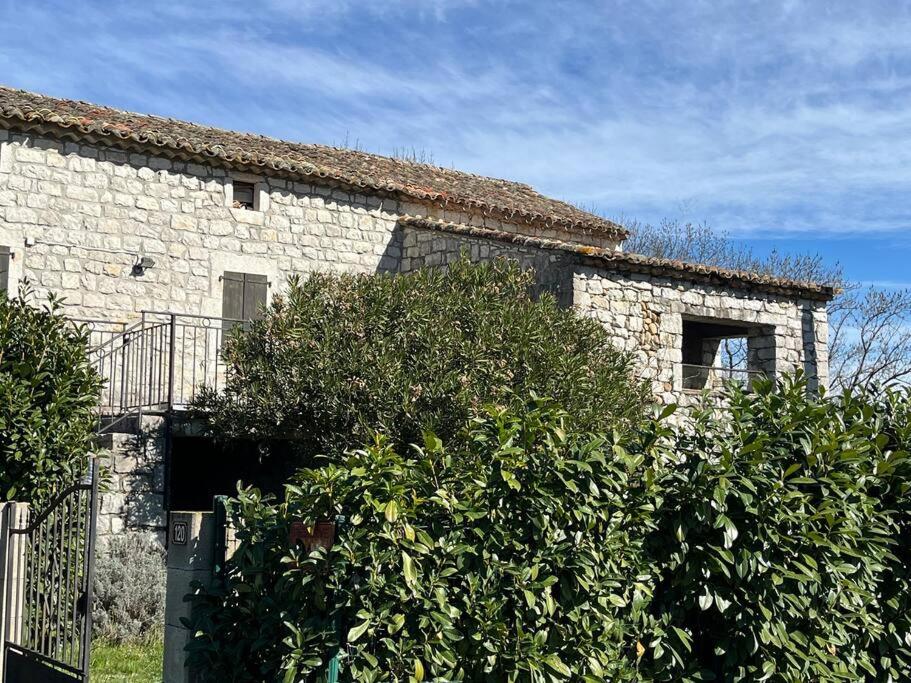 un bâtiment en pierre avec une haie devant lui dans l'établissement Maison de Campagne au bord de l'eau, à Saint Alban Auriolles