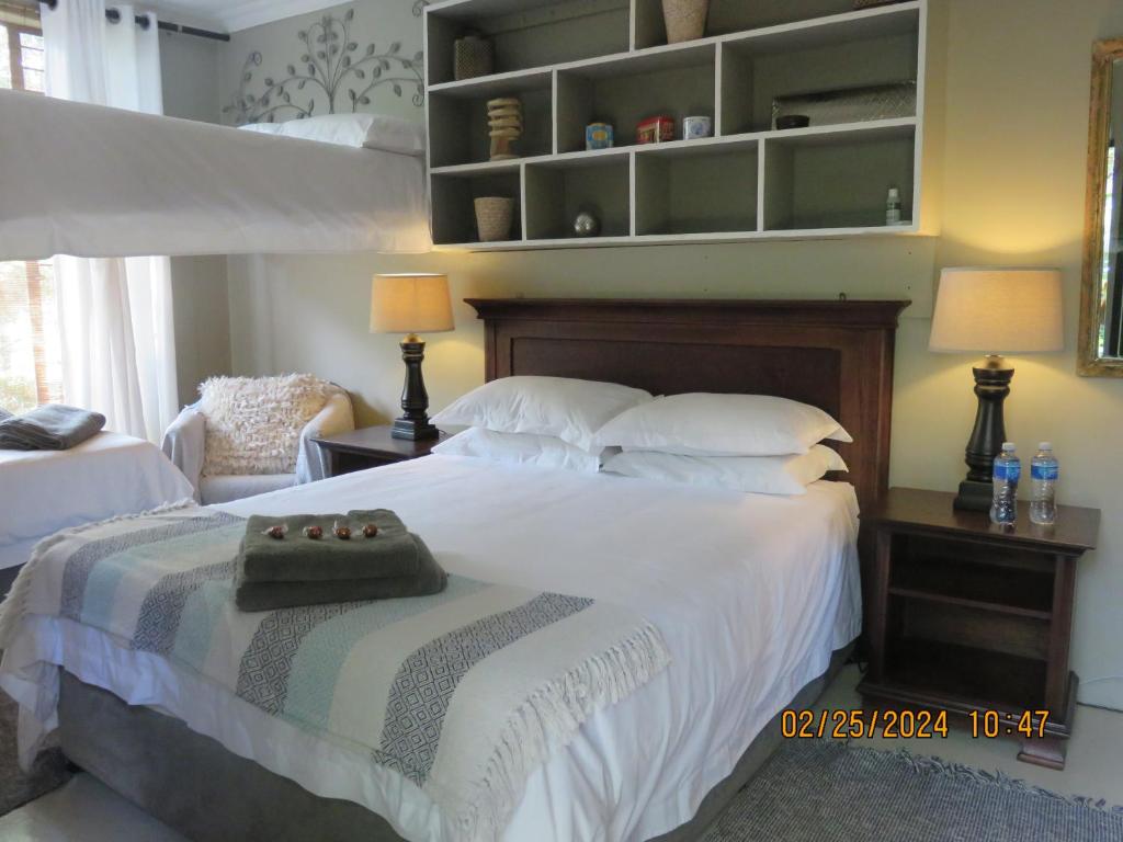 - une chambre avec un grand lit blanc et une grande tête de lit dans l'établissement Beni Apartment, à Pretoria