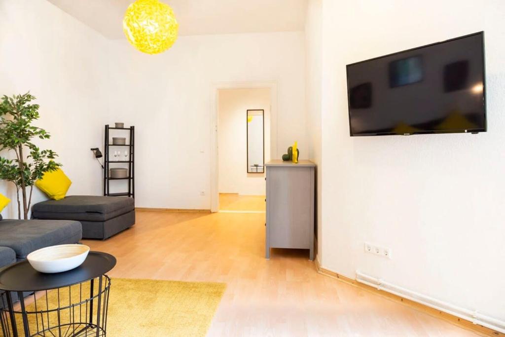 a living room with a couch and a tv on a wall at Spacious Family Apartment at Mauerpark plus SelfCheckIn in Berlin
