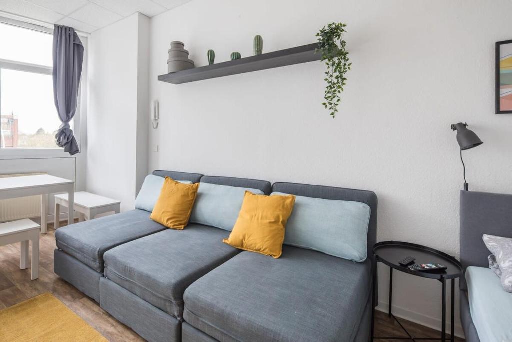a living room with a blue couch with yellow pillows at Spacious 2 BR Apartment Hamburg in Hamburg
