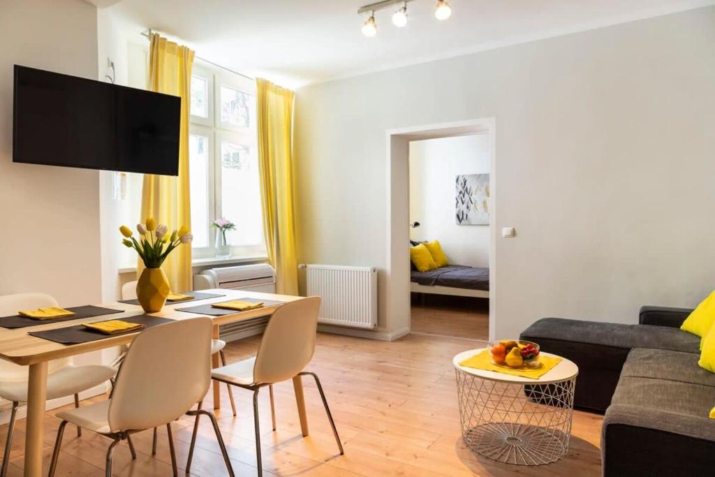een woonkamer met een tafel en stoelen en een bank bij Cosy Two BR plus Self Checkin plus Street Parking in Berlijn