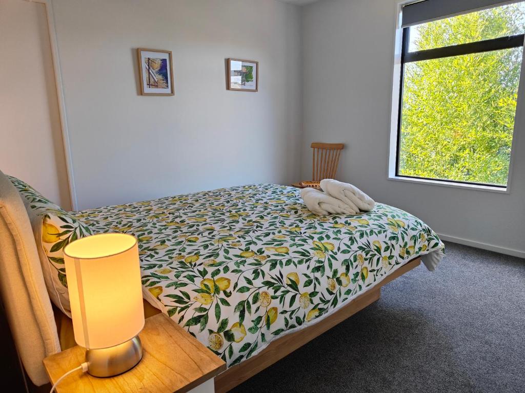a bedroom with a bed with a flowered blanket and a window at Tranquil Bamboo Oasis in Christchurch