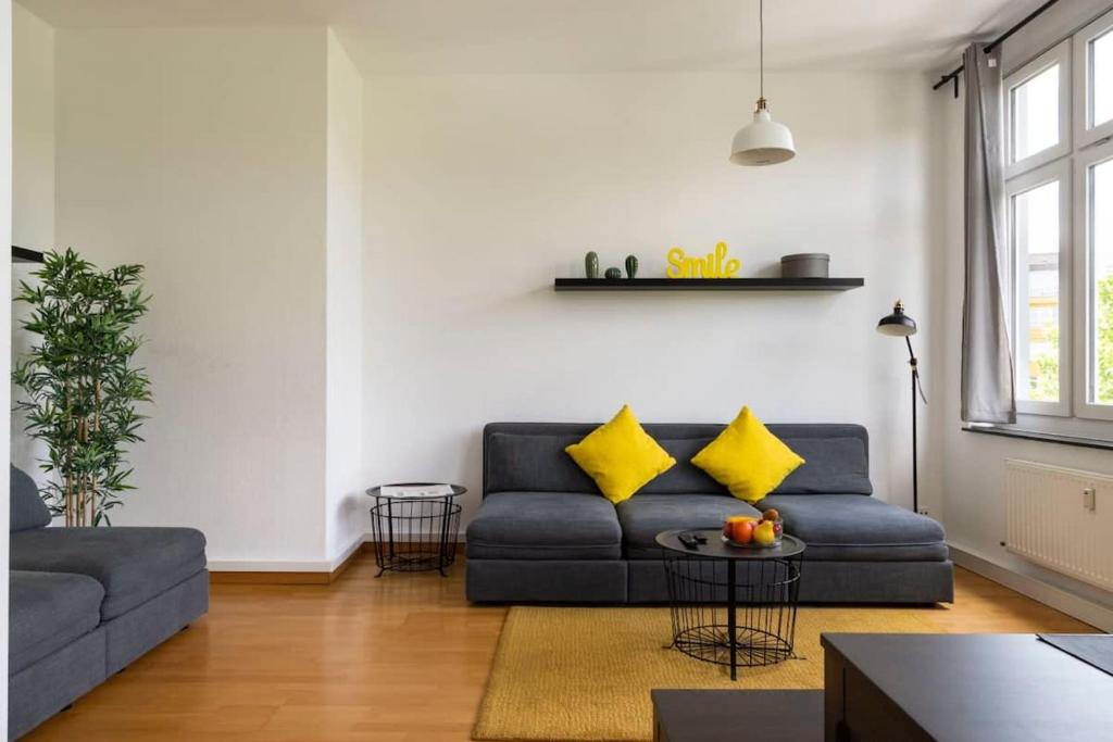 een woonkamer met een blauwe bank en gele kussens bij Central Big Apartment Self Checkin in Berlijn