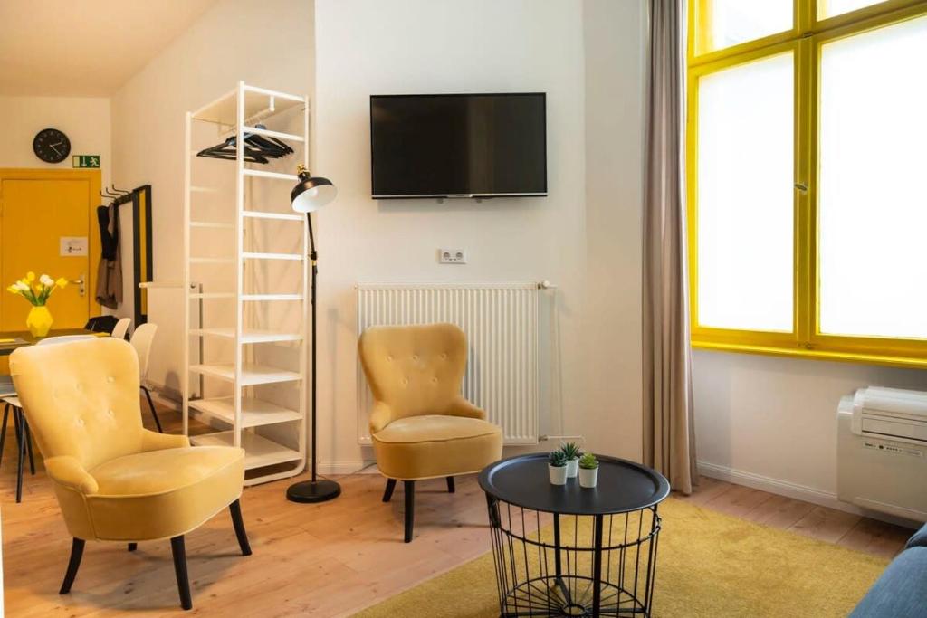 een woonkamer met 2 stoelen en een tv aan de muur bij Great Apartment close to Kudamm in Berlijn