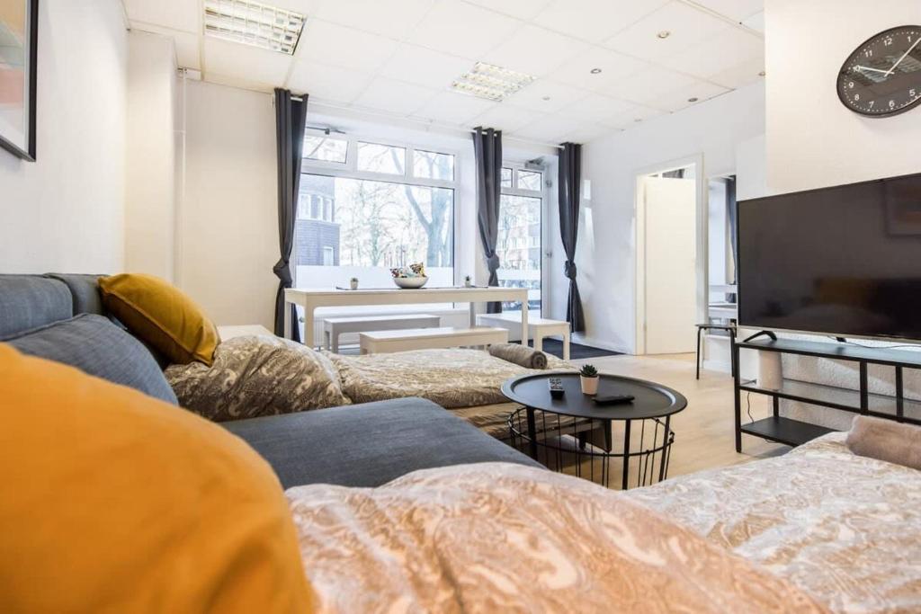 uma sala de estar com um sofá e uma televisão em Spacious Two BR Close To Stadtpark and Street Parking em Hamburgo