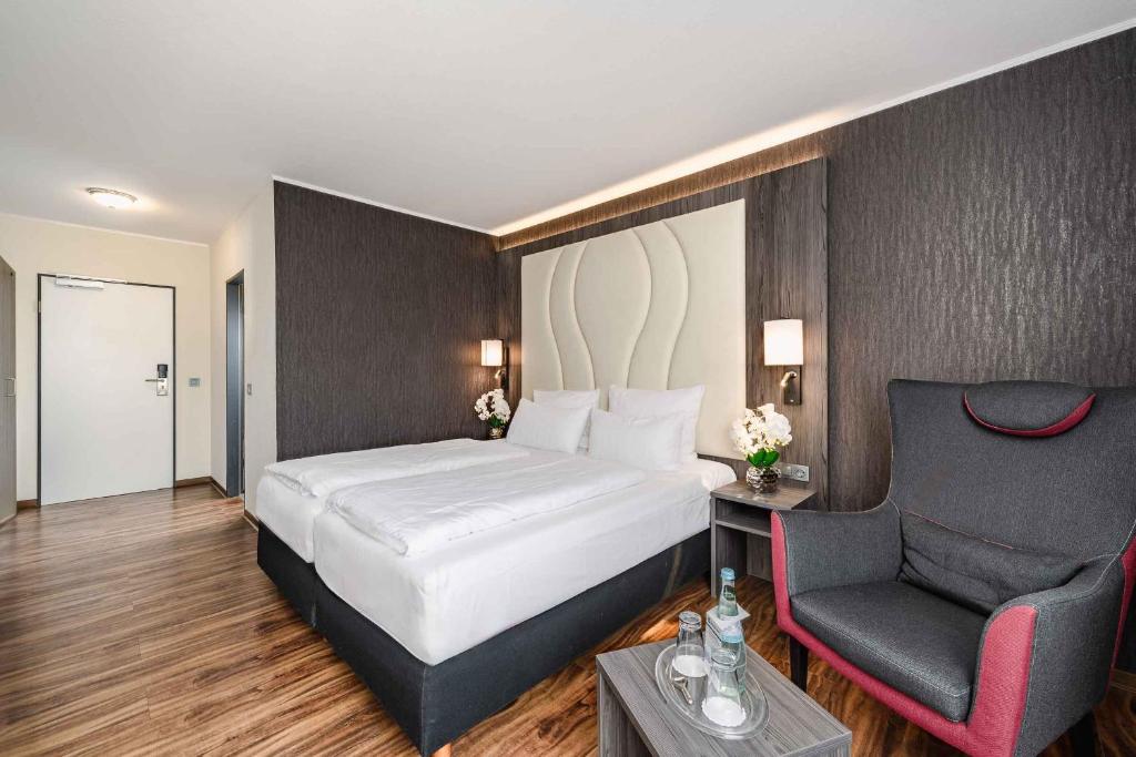 グレーヴェンブローホにあるBest Western PLAZA Hotel Grevenbroichのベッドと椅子付きのホテルルーム