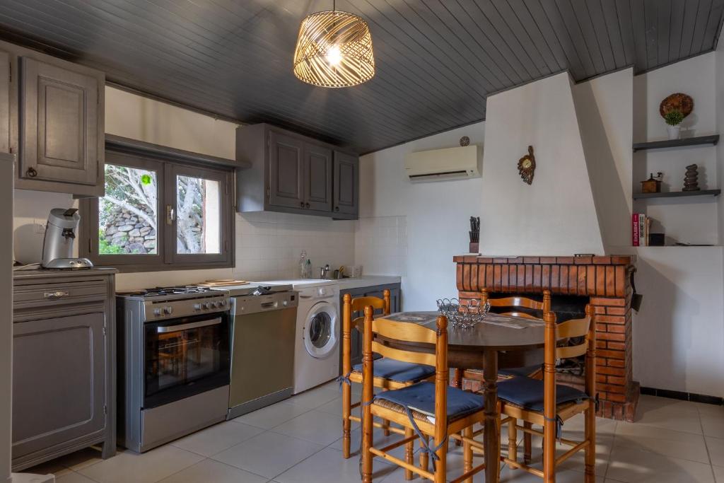 una cucina con tavolo, sedie e fornelli di Casa Calma - Maison à proximité des plages a Figari