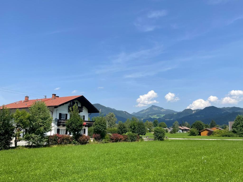 a house on a green field with mountains in the background at Ferienwohnung Bergpanorama in Oberaudorf