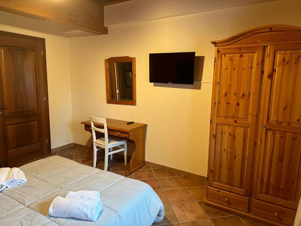 a bedroom with a bed and a desk with a television at La corte dell'ulivo in Polazzo