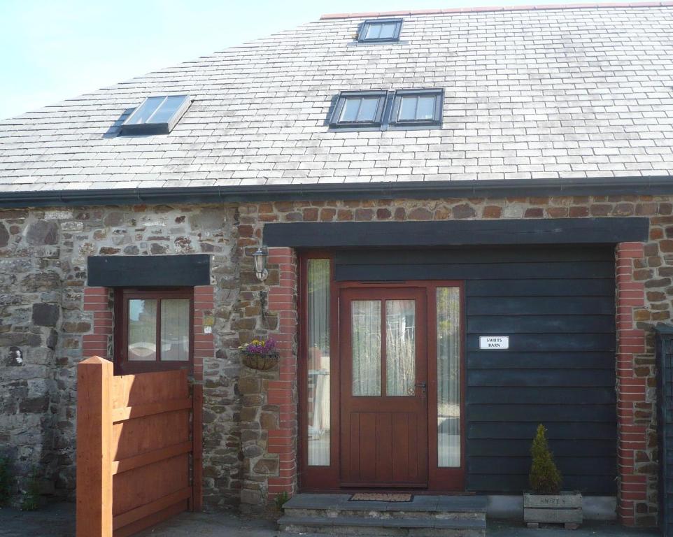 a brick house with a brown door and windows at Swifts Barn Stanbury Wharf in Holsworthy