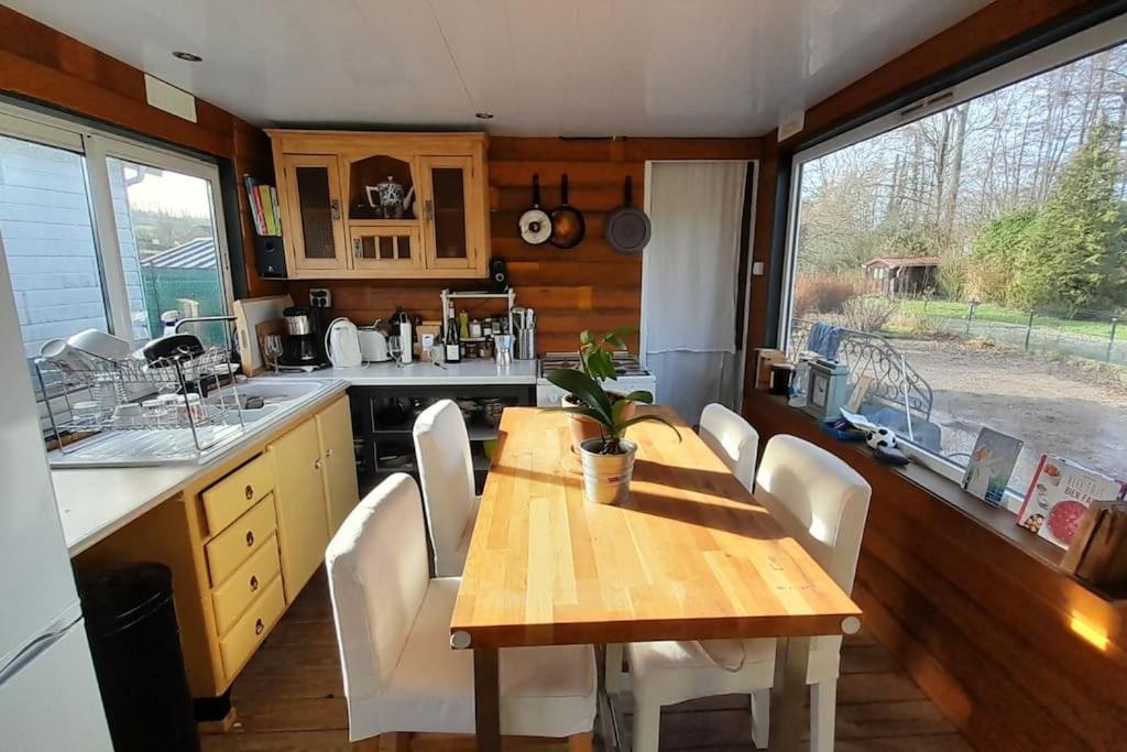 cocina con mesa de madera y sillas blancas en Le Petit Cavron, en Cavron-Saint-Martin