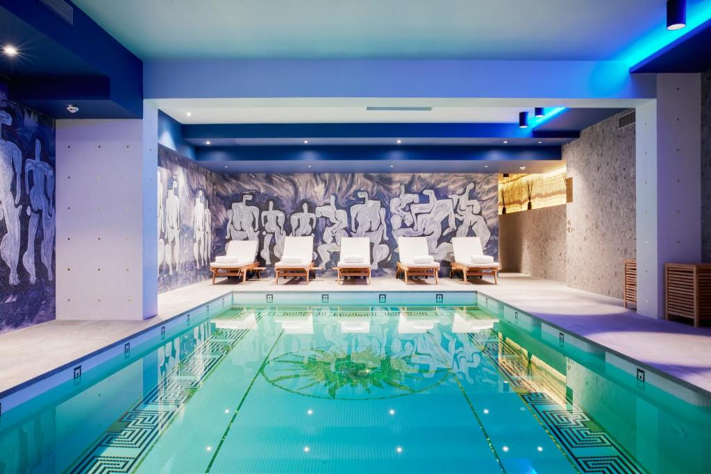 a swimming pool with chairs and a painting on the wall at Juliana Hotel Brussels in Brussels