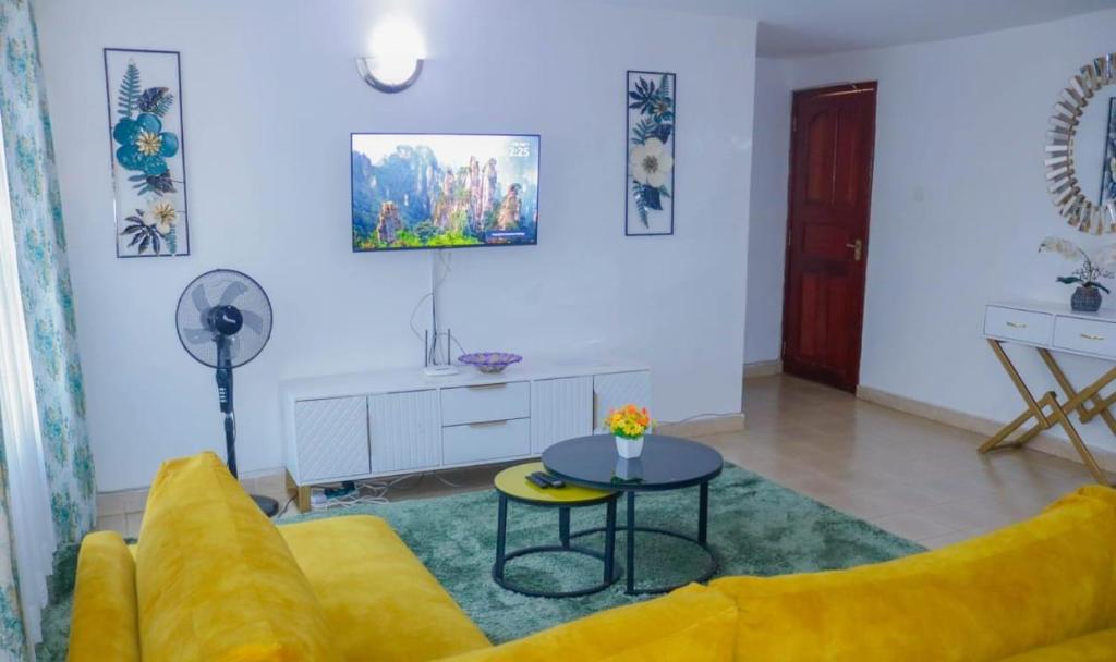 uma sala de estar com um sofá amarelo e uma mesa em Janos Luxury em Kisumu