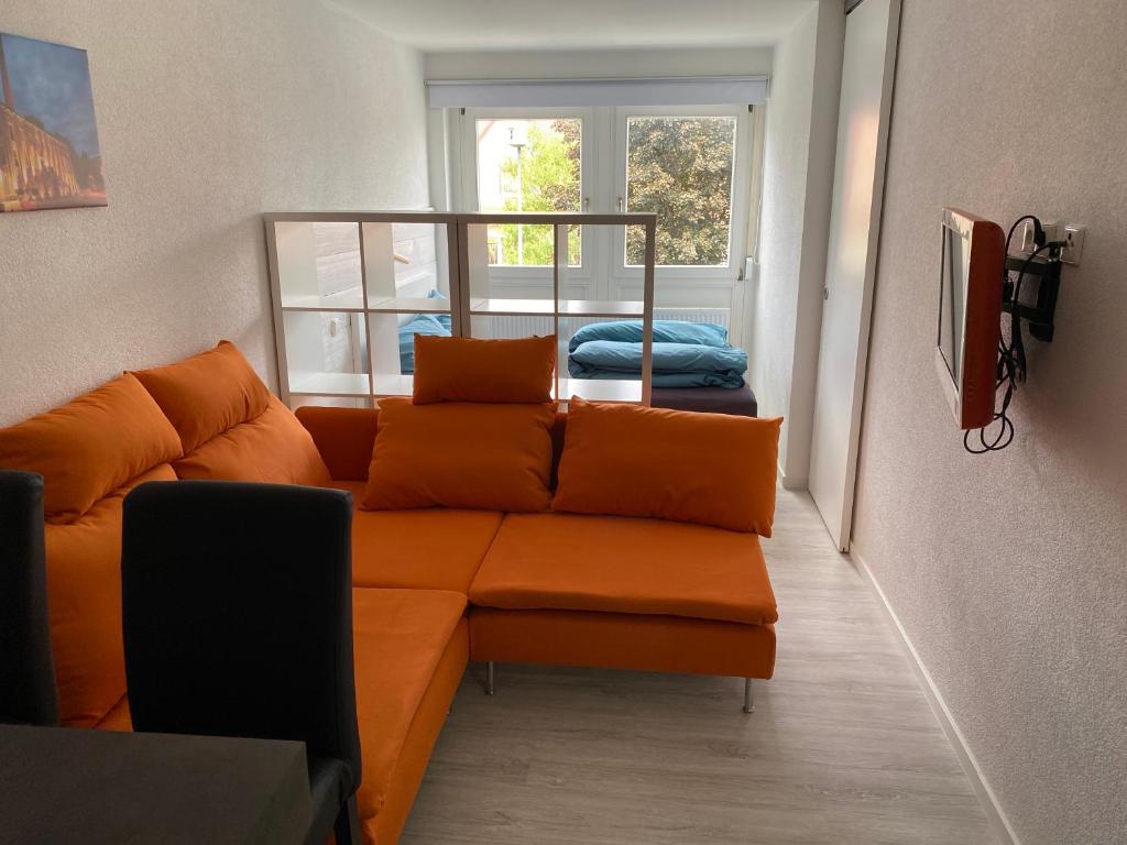 a living room with an orange couch and a window at Ferienwohnung Leonie in Rottweil in Rottweil