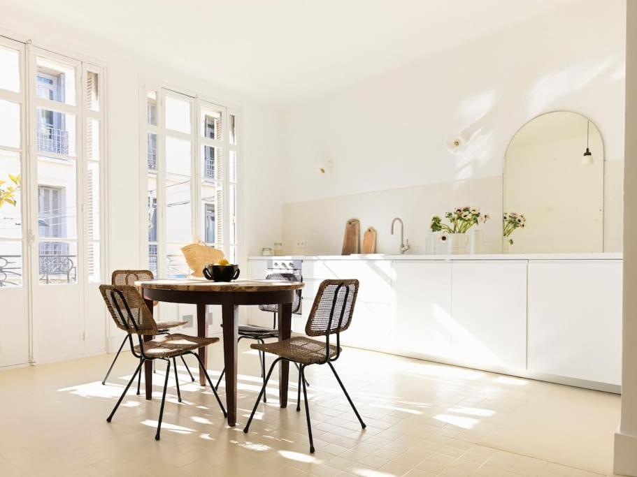 - une cuisine blanche avec une table et des chaises en bois dans l'établissement Le 6 _ Appartement d'exception, à Vence