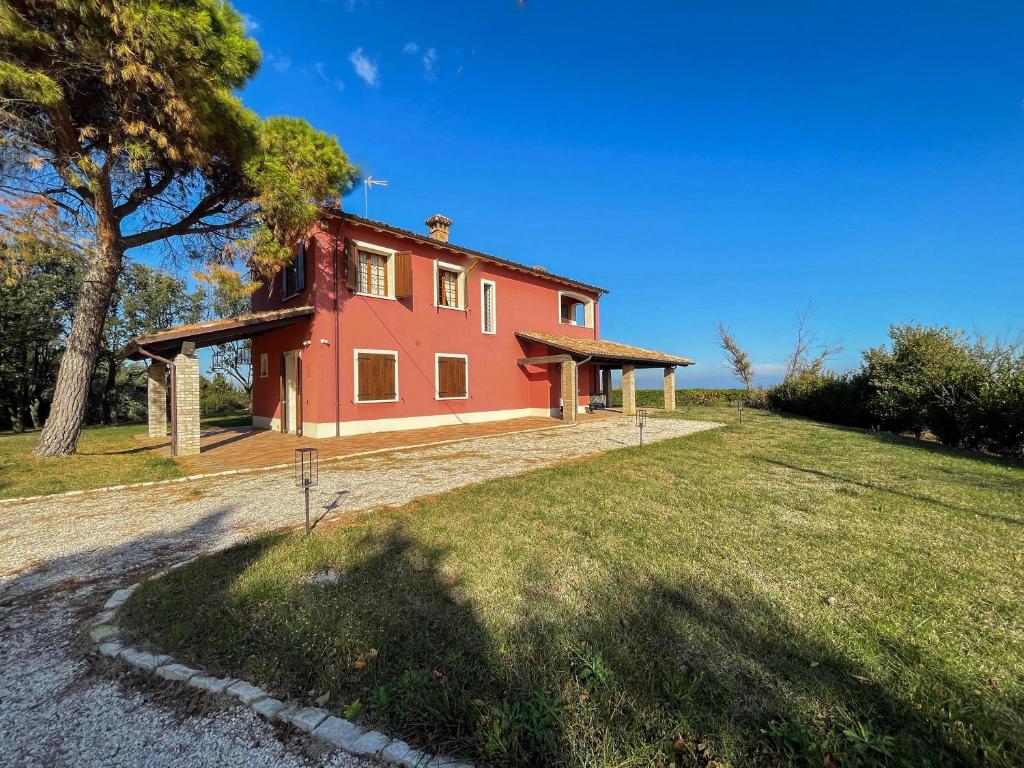 uma casa vermelha numa colina com uma árvore em Villa Villacolle by BarbarHouse em Mondolfo