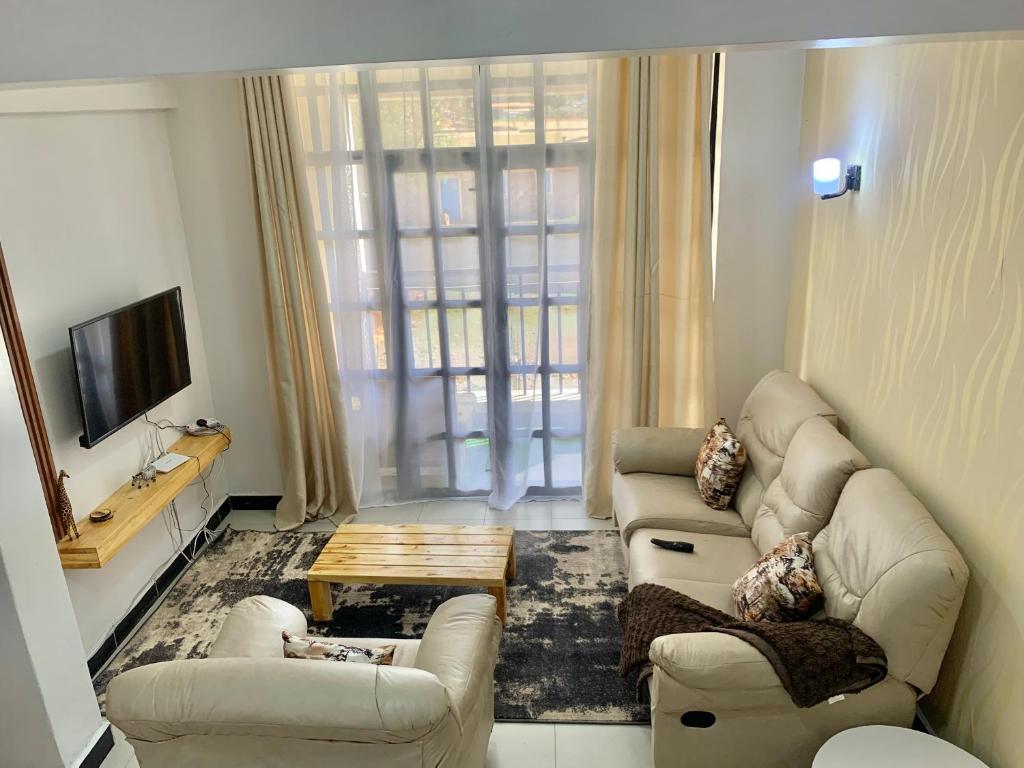 a living room with two couches and a tv at Rorot 1 bedroom Modern fully furnished space in Annex Eldoret with free wifi in Eldoret
