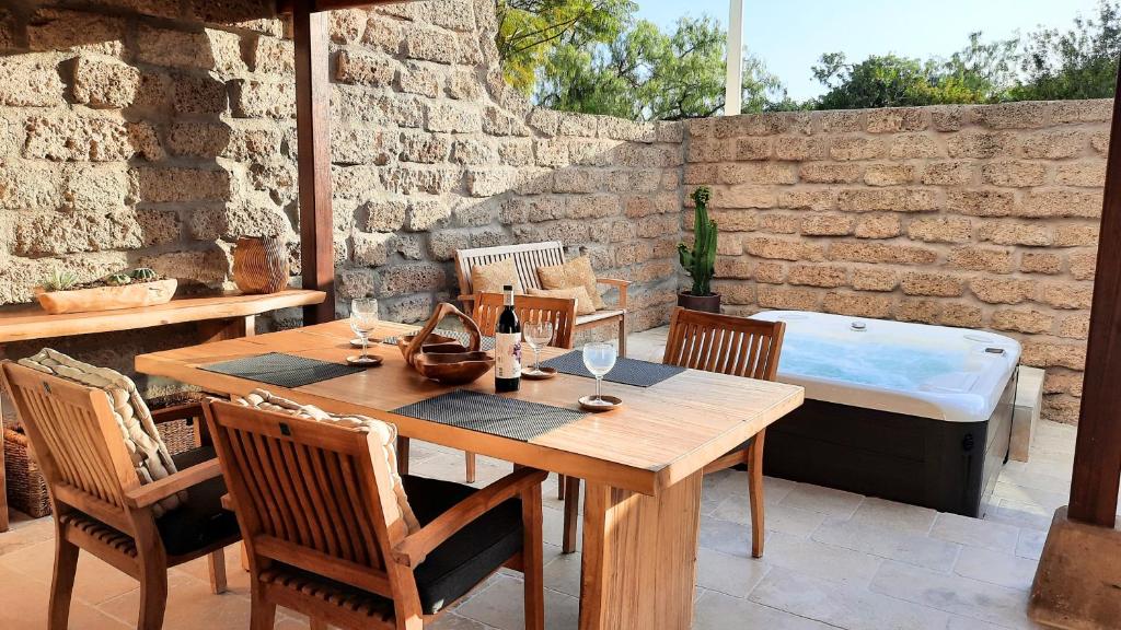 einen Holztisch mit Stühlen und eine Badewanne auf der Terrasse in der Unterkunft Casa Waldeck en Jardines del Duque in Adeje