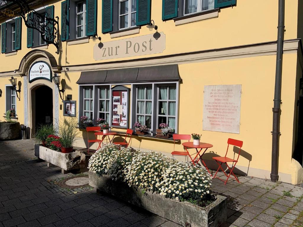 ein Restaurant mit Tischen und Stühlen vor einem Gebäude in der Unterkunft Posthotel Arnold in Gunzenhausen