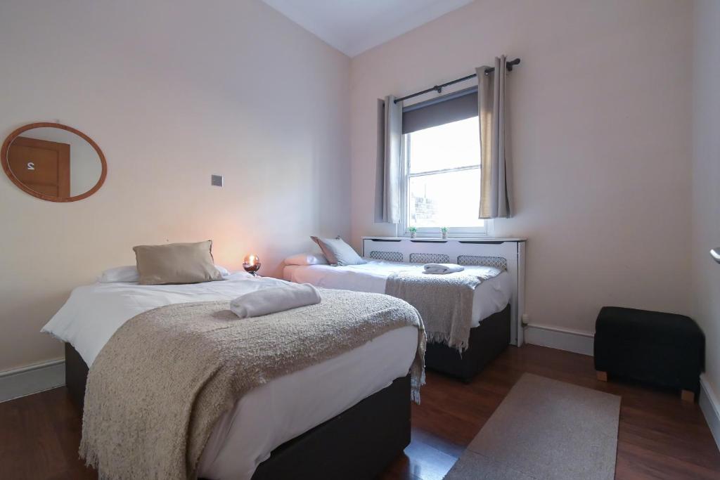 a bedroom with two beds and a window at Queensway Flat by DC London Rooms in London