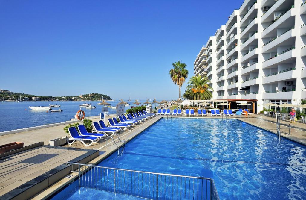 a swimming pool with chairs and a large building at Globales Verdemar in Santa Ponsa