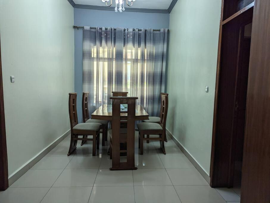 a dining room with a wooden table and chairs at Home in kigali in Kigali